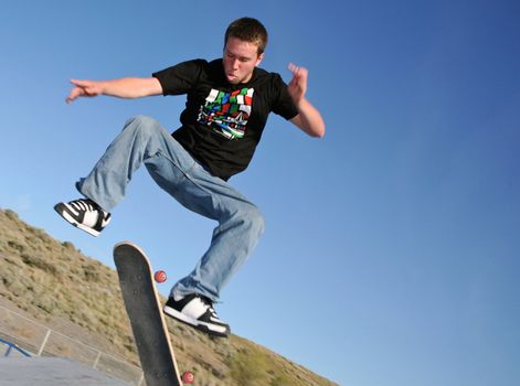 A young skater jumping over a ramp in a park
