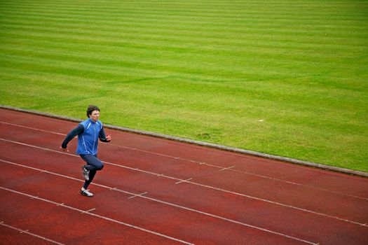 An young athlete running on the track and approaching the finsh line
