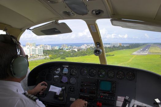 pilot landing on the airstrip near a tropical town on the ocean shore