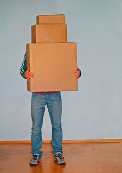 A young man carrying cardboard boxes.
