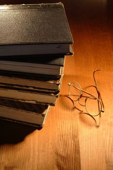 Very old eyeglasses near books lying on nice wooden background