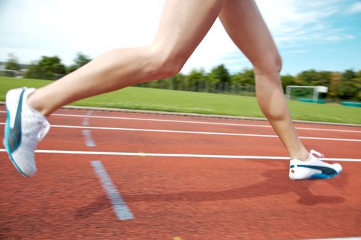 A female athlete running on a track in summer
