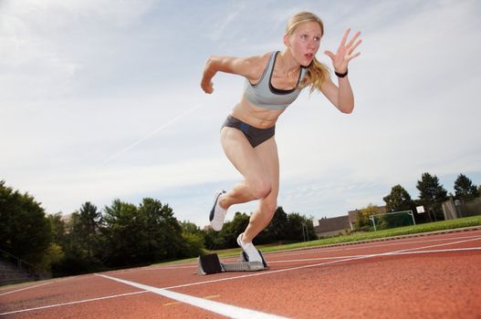 A female athlete runs off the starting block
