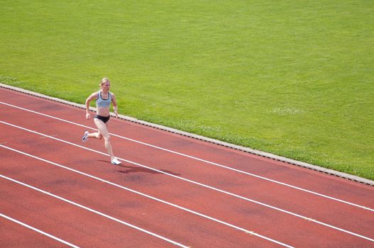 A female athlete running on a track in summer
