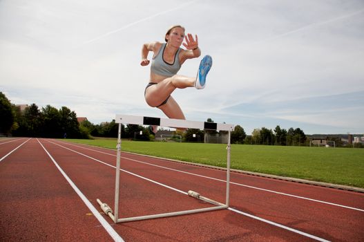 A young athlete jumping over a hurdle
