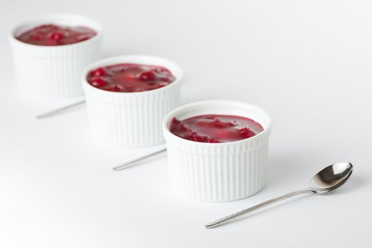 Three mini cheesecakes in white cups with small spoons