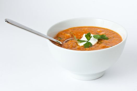 Soup in white bowl with a spoon on white background