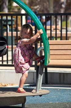 Cute little European toddler girl having fun at the playground in park