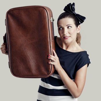 Portrait of a beautiful fashion woman posing and holding a old suitcase