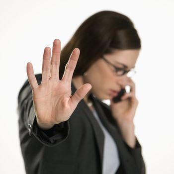 Caucasian mid adult professional business woman talking on cell phone holding hand out to stop viewer.