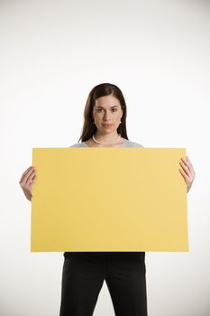 Caucasian mid adult professional business woman standing holding up blank yellow sign.