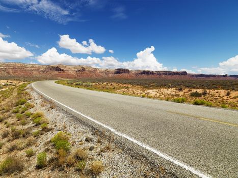 Rural Utah scenic road with mountain range in distance.