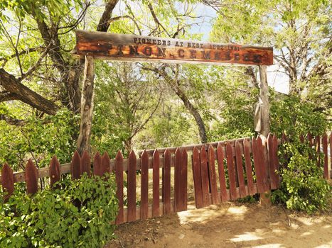 Pioneer cemetery entrance with gate and sign in woods.