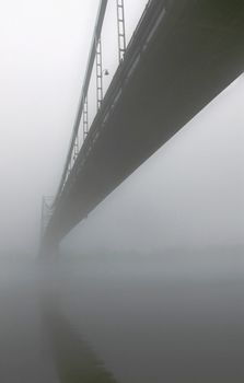 View of entire length of bridge with fog obscuring top of bridge.