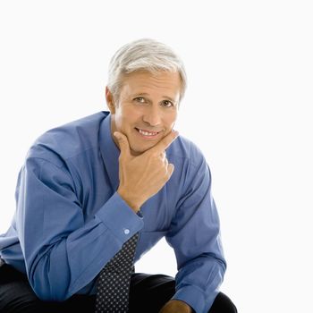 Middle aged Caucasian man smiling at viewer with hand to chin.