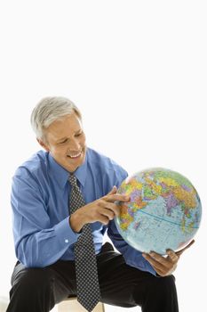 Middle aged Caucasian man holding globe and pointing.