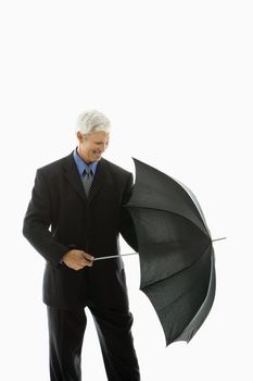 Caucasian middle aged businessman closing umbrella.