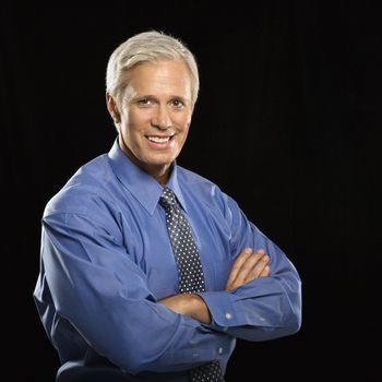 Caucasian middle aged businessman smiling at viewer with arms crossed.