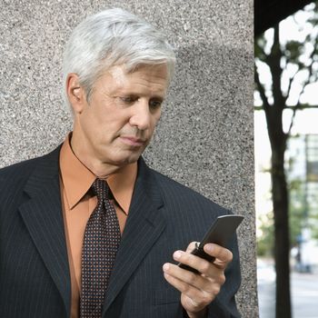 Caucasian middle aged businessman looking down at cell phone.