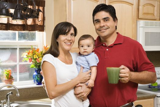 Hispanic family portrait in home kitchen with baby.