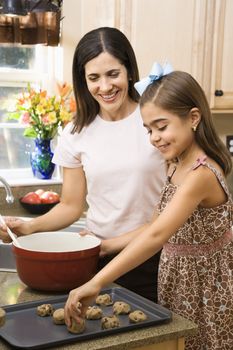 Hispanic mother and daughter in kitchen making cookies.