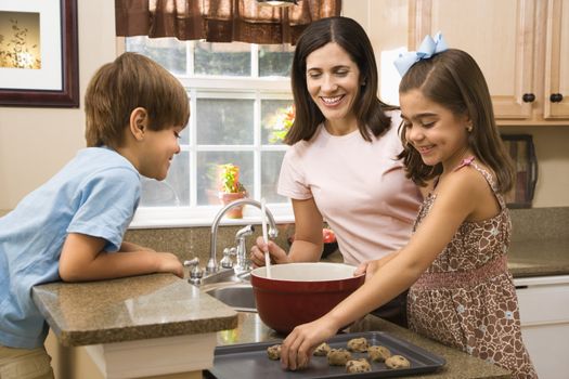 Hispanic mother and children in kitchen making cookies.