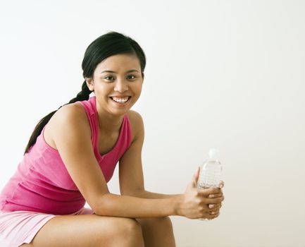 Portrait of smiling young Asian woman holding bottle of water.