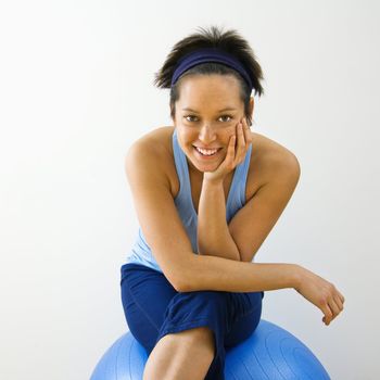 Portrait of young woman sitting on fitness balance ball smiling.