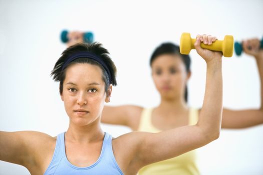 Young women at gym lifting hand weights.