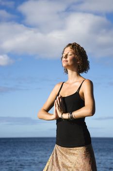 Caucasian young adult female meditating by the Pacific ocean of Maui, Hawaii.