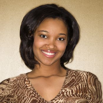 Close-up portrait of African-American young adult female smiling at viewer.