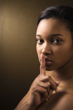 African-American young adult female shushing the viewer.