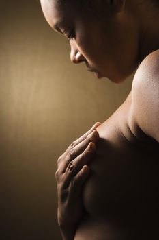 Young adult African-American female giving self breast exam.