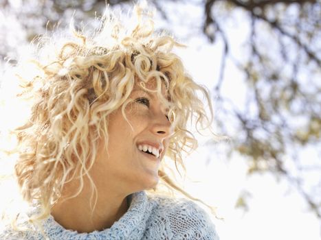 Head and shoulder portrait of attractive young woman with curly blond hair smiling in Maui, Hawaii.