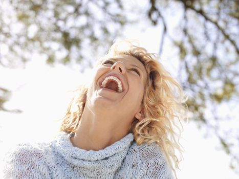 Pretty young blond woman in Maui, Hawaii leaning head back and laughing.