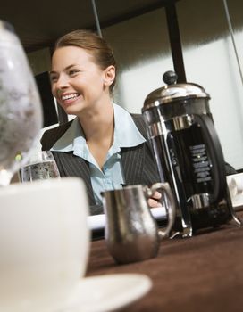 Caucasian businesswoman smiling at table with coffee and beverages.