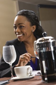 African American businesswoman smiling and sitting at table in restaurant.