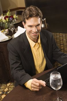 High angle view of Caucasian businessman with laptop in restaurant.