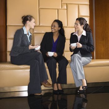 Businesswomen drinking coffee and conversing.