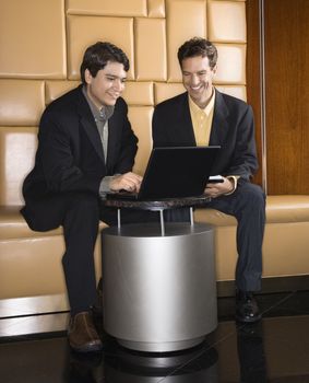 Businessmen talking and viewing laptop computer.