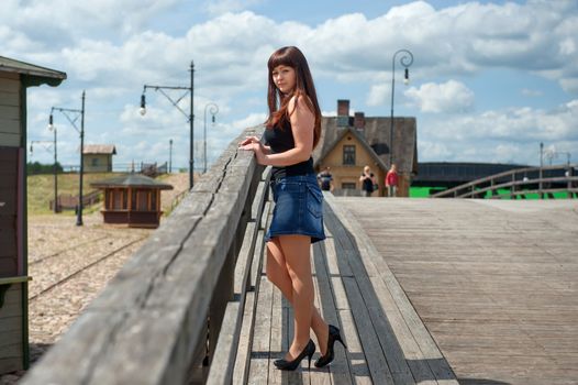 Young, sexy  woman in short skirt stand on the old-time bridge.
