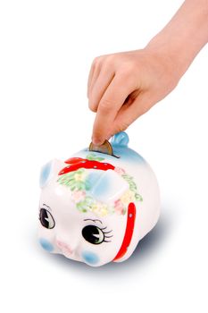 The hand lowering a coin in a pig-coin box