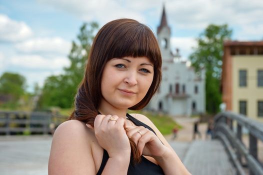 Portrait of young, beautiful woman with church on the background.
