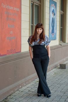 Young, beautiful woman stand on the street near old-time poster.