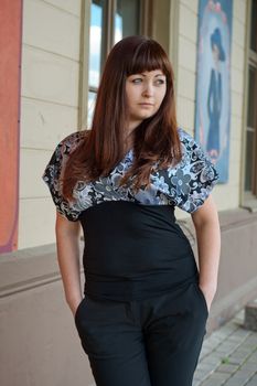 Young, beautiful woman stand on the street near old-time poster.