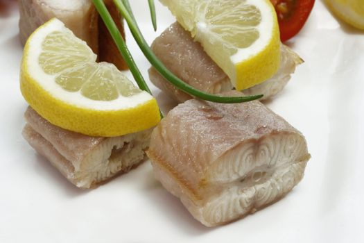 Pieces of smoked eel on a plate with garnish