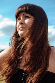 Portrait of young, beautiful red-haired woman with blue sky on the background.
