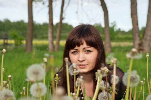 Portrait of young beautiful woman in meadow of dandelions.
