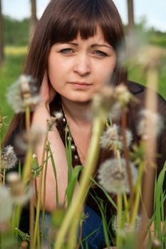 Portrait of young beautiful woman in meadow of dandelions.