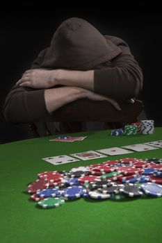 Man with sun glasses playing poker on green table. Chips and cards on the table.